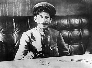Joseph stalin sitting at a table in 1918.