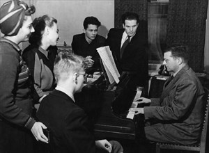 Soviet composer, dmitri shostakovich, at his piano with a group of students from his theory and composition class, moscow, ussr, october 1947.