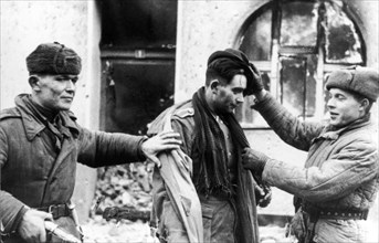 The german officer, who tried to escape in civilian dress, was taken prisoner by these two soviet tommy-gunners.