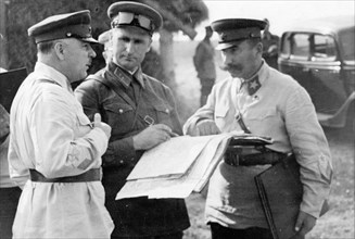 Peoples' commissar of defense, marshall kliment voroshilov, division commander vasily sokolovsky, and marshall semyon budyonny looking over a map during tactical exercises in the moscow military distr...