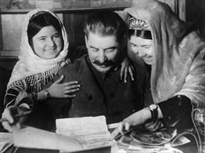Joseph stalin with two young women collective farm workers from tadjikistan soviet republic at a conference of cotton farm workers, january 1936, ussr.
