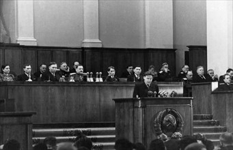 Nikolai alekseyevich voznesensky, chairman of the state planning commission of the ussr, speaking at the joint session of the supreme soviet of the ussr and the soviet of nationalities, seated behind ...