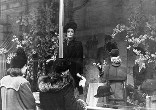 Two women looking at coats and hats on display in a window of the central department store in moscow, 1940s.