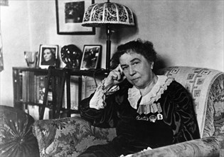 Ambassador alexandra kollontai at her home in moscow, on the bookshelf behind her is a portrait of the minister of republican spain, isabel de palencia, the author of her biography, april 1946.