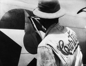 World war 2, lend-lease, a man painting out the american insignia with red paint for delivery of the plane to russia, iran.