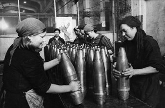 A team of civilian women packers putting grease onto artillery shells at a munitions factory during world war 2.