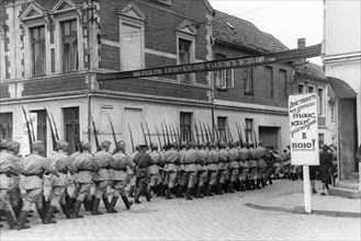 World war 2, men of a soviet garrison in germany marching to the drill grounds, july 1945, sign reads: 'approach learning the same way as one would approach going to battle,'.