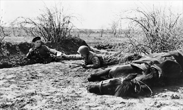 A red army scout handing over his report to another soldier at an advanced observation post on the south-western front while his well trained horse lies flat for safety, world war ll.