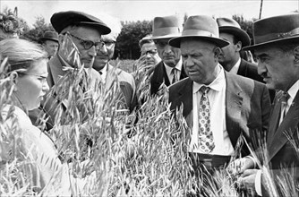 Nikita khrushchev, accompanied by a, mikoyan, suslov (behind khrushchev, left), and trofim lysenko (wearing cap, left) on a visit to the scientific-experimental base 'lenin hills' of the institute of ...