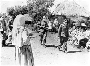 A german officer is sent under escort by a soviet soldier through a village in the orel area during world war ll.