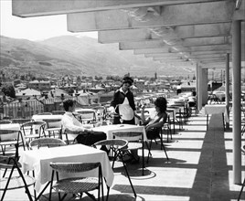 A young couple having drinks on the terrace of a new hotel for foreigners near ossogovo mountain in kyustendil, bulgaria, 1965.