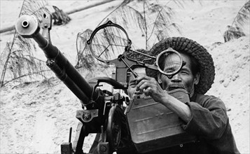 Two old fishermen from the village of nam ngan (or donghang) manning an anti-aircraft machine gun to defend against american air attacks, north vietnam, 1968.