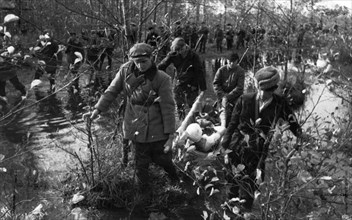 World war 2, partisans of western byelorussia returning from a successfully accomplished assignment, carrying a wounded comrade on a stretcher through a marsh.