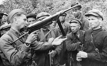 World war 2, a red army soldier explaining the workings of a captured herman automatic rifle to a group of partisans, september 1941.