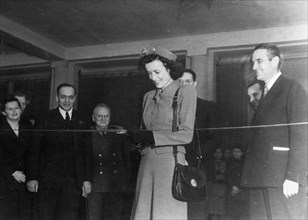 Miss harriman cutting the ribbon at the opening of the 'prefabricated housing in the usa' exhibition at the moscow architects club, 1940s, on the right is us ambassador william averell harriman.