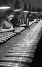 Soviet artillery shells undergoing quality control inspection by civilian women workers at a munitions plant during world war2.