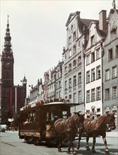 Horse drawn streetcar on a street in gdansk, poland with city hall in the background, 1965.
