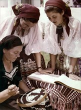 Award winning folk artist mrs, jozsef kovacs (left), teaching two young women embroidery by the newly erected folkart house in the village of decs in tolna county, 1950s.