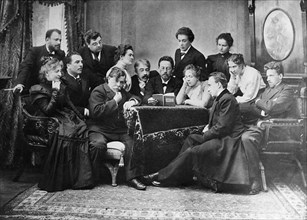Anton chekhov reads his play 'the seagull' to actors of the moscow art theatre, 1899, chekhov center with book in hand, director and actor konstantin stanislavsky to his left, standing beside stanisla...