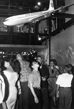 People examining a model of a boeing 707 on display at the main pavilion of the american national exhibition in moscow, ussr, august 1959, 'it seems that our plane is better ,,,' (from the original ca...