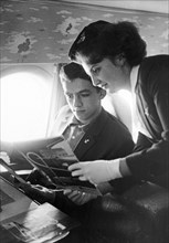 Stewardess olga vaskovskaya offering new magazines to a passenger aboard a tu-134 airliner, october 1965.