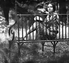 A beautiful young woman sitting on a bench reading a book in a leningrad park, september 1978, ussr.