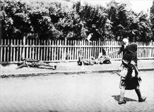 Women walk past people dying of starvation in a documentary photograph displayed at an exhibition in kiev, dedicated to holodomor, the great ukrainian famine of early 1930s.