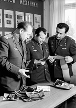 Soviet cosmonauts alexei leonov, yuri gagarin and pavel popovich looking at printed photo transmissions from the luna 9 moon probe, 1965.