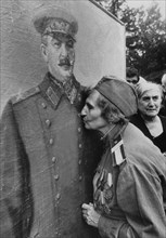 A georgian woman - a world war 2 veteran - kissing a portrait of josef stalin, gerogian-born dictator who led the ussr against the nazis, tbilisi, georgia, victory day celebration.
