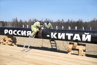 Amur region, russia, april 27, 2009, workers welding the first segment of a branch pipeline which will run into china from the eastern siberia – pacific ocean (espo) oil pipeline, the slogan on the pi...