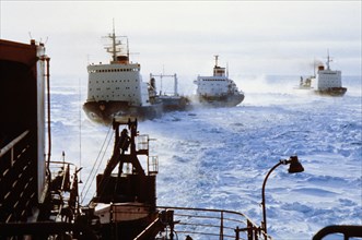 A convoy of russian icebreakers clearing a shipping lane through arctic ice.