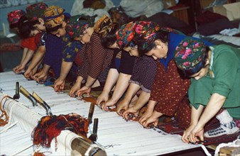 Turkmen women weaving rugs by hand at a factory in ashgabat (ashkabad), turkmenistan.
