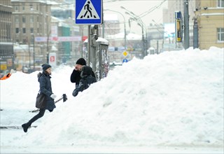 Moscow, russia, february 23, 2010, pedestrians walk past tall snow piles in a central moscow street.