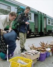 Irkutsk region, russia, august 11, 2004, passengers buying fish offered by residents of the village of slyudyanka, on the lake baikal, on railway station.