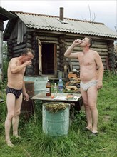 Two men drinking beer and vodka with zakuski after a sauna - also the russian style, ivanovo region, russia, august 2005.