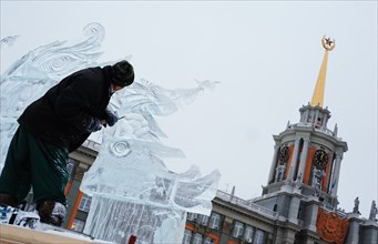 Yekaterinburg, russia, december 28, 2011, man carving an ice sculpture during an international ice and snow sculpture festival, in 1905 square.