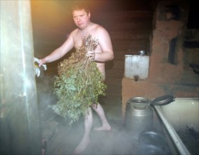 A man with birch branches in the shower room of the banya (russian steam bath) in elnat (yelnat) village in the ivanovo region of russia, 2006.