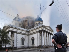 Policeman watching a fire at troitsky (trinity) cathedral being extinguished by a helicopter in st, petersburg, russia, august 25, 2006.