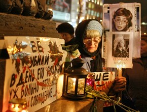 A mourner holds a placard and a lit candle during a rally in pushkin square, marking the 40 day anniversary of anna politkovskaya's death, moscow, russia, november 15, 2006.