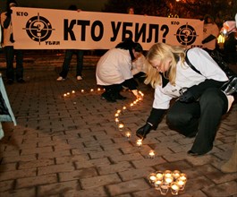 Mourners arrange lit candles into a large question mark in front of a banner reading 'who's the killer?' during a rally in pushkin square, marking the 40 day anniversary of anna politkovskaya's death,...