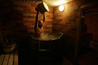 A man pouring water on himself at a banya (sauna) at the pushkarskaya sloboda hotel in russia.