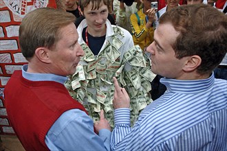 Russia's first deputy pms sergei ivanov and dmitry medvedev, l-r, look at each other as a man wearing dollar bills stands nearby at the summer camp of the pro-putin nashi (our people) youth movement a...