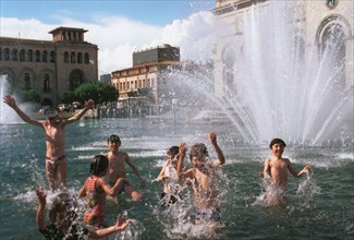 A hot day in yerevan, children cool off in the fountain in the central square, armenia, 1996.
