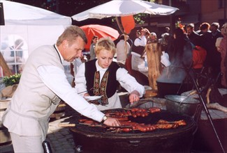 The folk festival in dom square, riga, latvia, peasants' sausages are frizzled according to an old technology on the grates of cast-iron pans,2003.