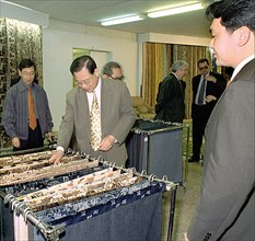Orenburg, russia, june 16 2003: head of the chinese delegation from shantung province chao chihao, centre, seen inspecting the assortment of the materials, produced by 'orenteks' enterprise during his...