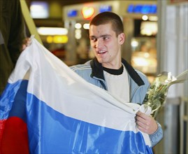 Moscow, russia, december 3 2002: russian tennis player mikhail youzhny, who scored the decisive point and brought the win of the davis cup to the russian team , pictured with a russian flag at the she...