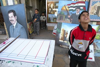 Baghdad, iraq, february 17 2003: a young resident of bagdad pictured viewing some works of a street artist in downtown the city.