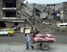 Kabul, afghanistan 2/03, a man hauls a cart loaded with food through the ruined streets of the capital.