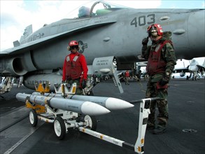 Caption: tas15: mediterranean sea, uss theodore roosevelt, march 22, 2003, servicemen removing unused aim-120 air-to-air missiles from a fa18 hornet fighter after the aircraft returned on board of the...