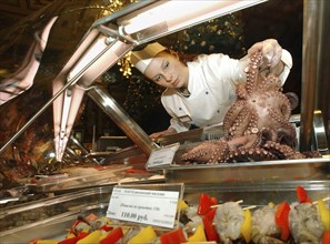 Sales person handling an octopus at the famous yeliseyevsky gourmet supermarket which reopened after renovations in central moscow on saturday, november 29, 2003.